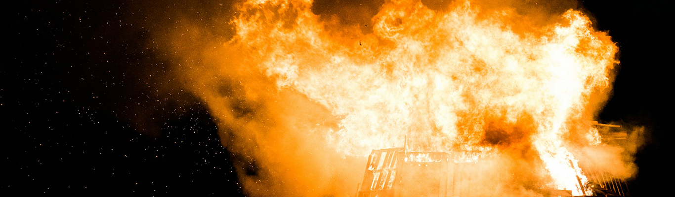 Large fire and smoke engulfing a structure at night
