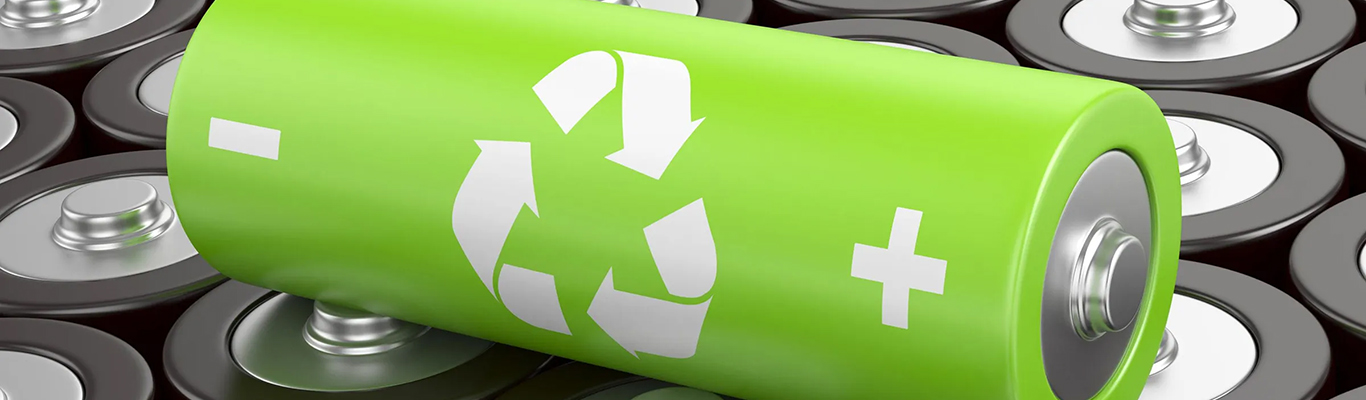 Green battery with recycling symbol placed on top of other standard batteries